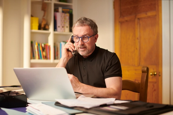 Man working on laptop while talking on phone